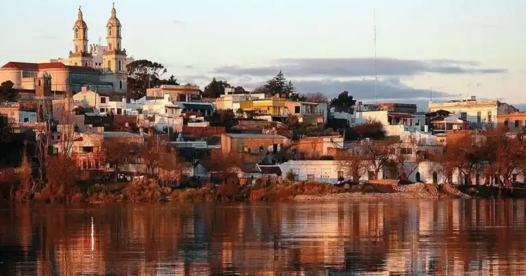 Ciudad patagónica reflejada en río al atardecer dorado