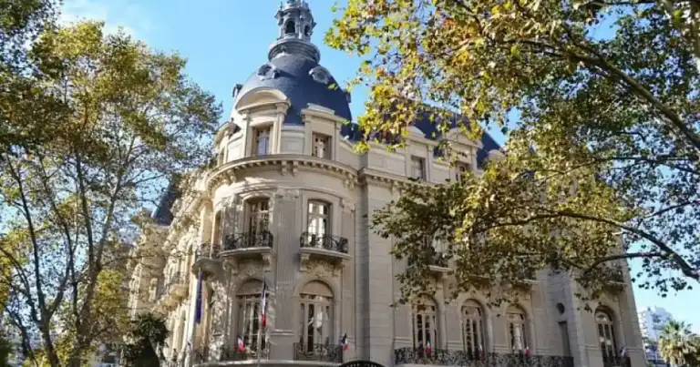 Edificio de arquitectura neoclásica con cúpula y árboles alrededor