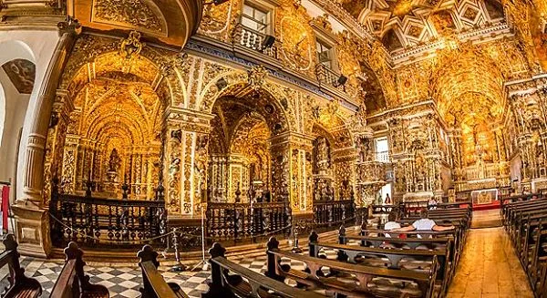 Interior de iglesia barroca con decoración dorada, techo abovedado y columnas