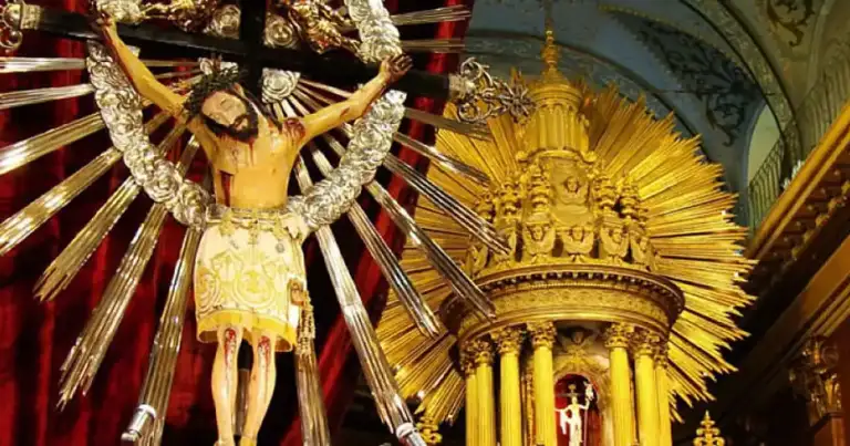 Interior de iglesia colonial con figuras religiosas doradas y rojas