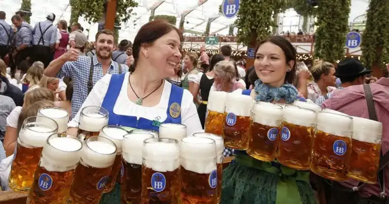 Mujeres en dirndl bávaro sirviendo jarras de cerveza en Oktoberfest