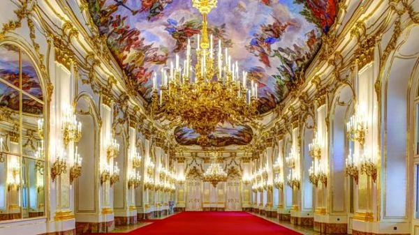 Sala de palacio con techo ornamentado, lámparas doradas y cortinas rojas