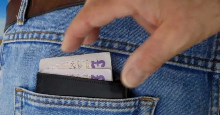 bolsillo traseo del pantalon con una billetera y una mano que intenta robarla