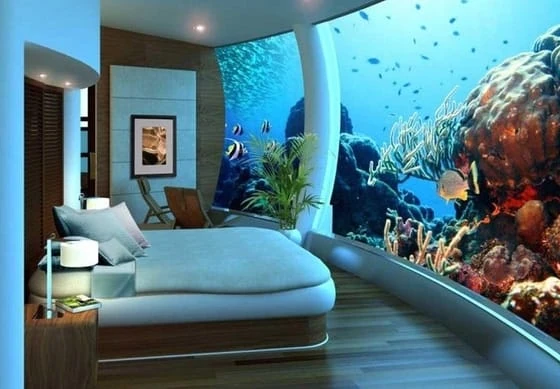 Dormitorio con cama junto a acuario gigante de peces y corales coloridos