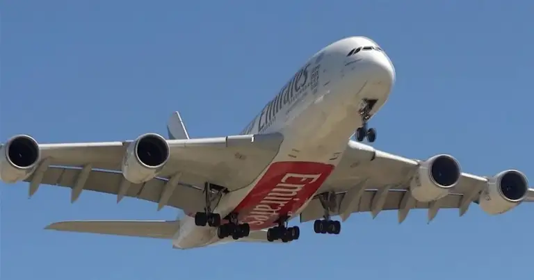 Avión comercial Emirates volando contra cielo azul