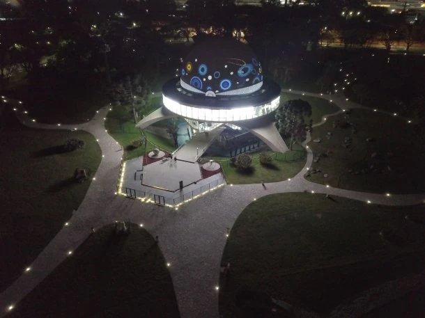 Planetario de estructura redonda con iluminación azul de noche rodeado de terreno