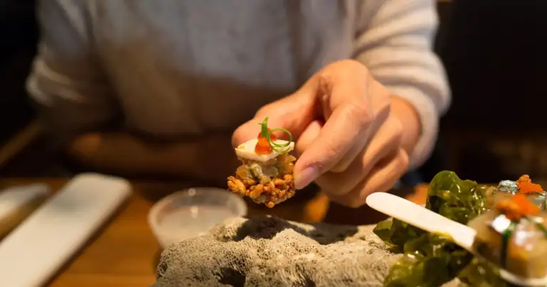 Persona compartiendo comida en un plato en una mesa de restaurante