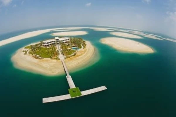 Isla artificial en forma de palma con edificios rodeada de agua turquesa