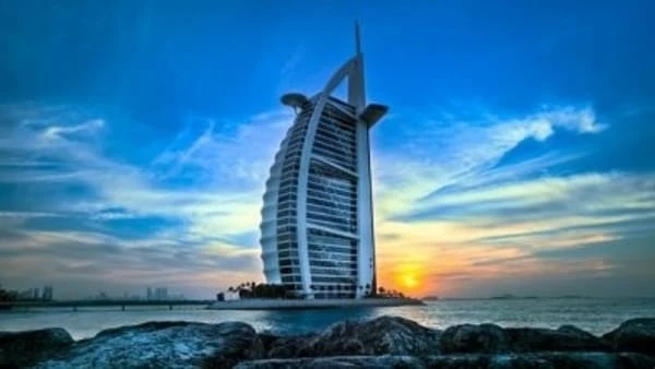 Hotel en forma de vela junto al mar al atardecer con cielo azul