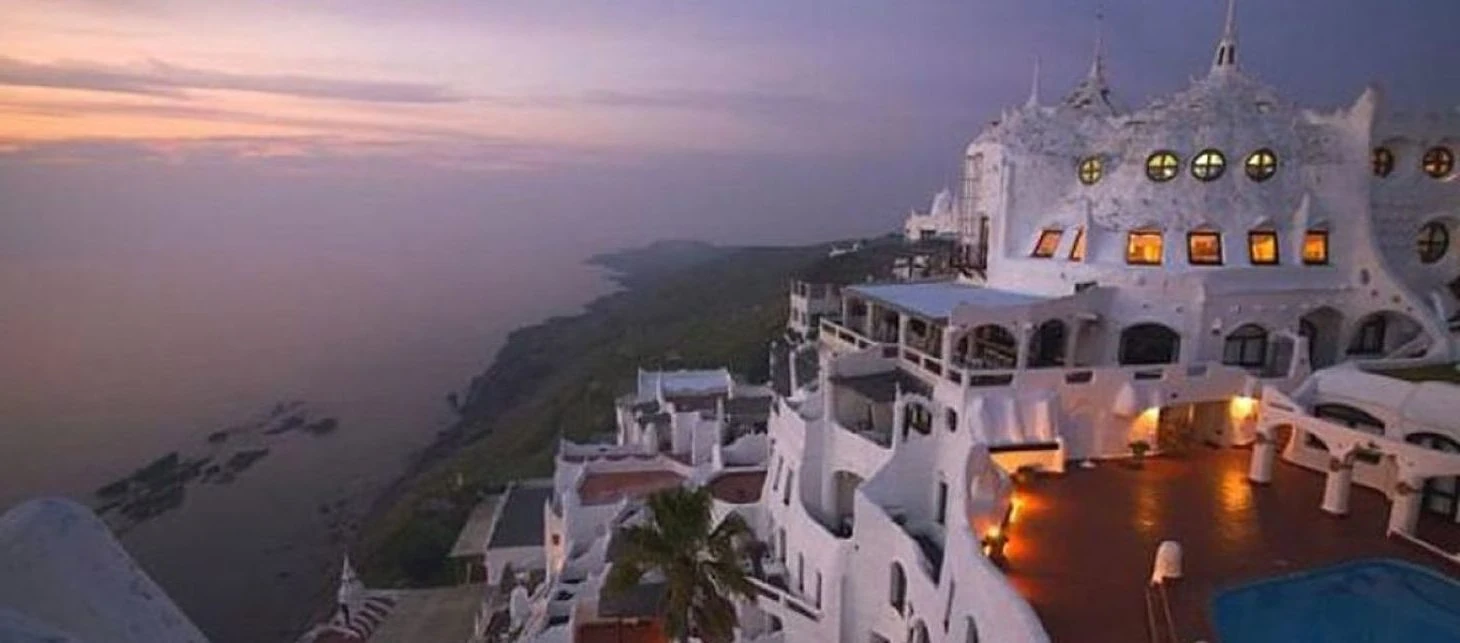 Hotel blanco moderno con iluminación nocturna en acantilado frente al mar