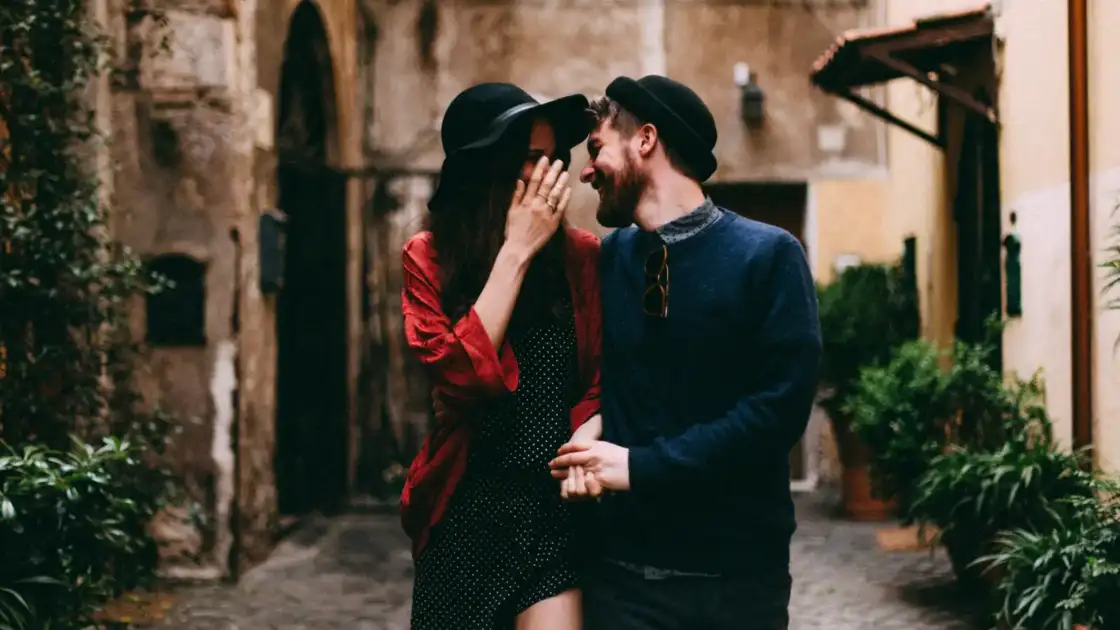 pareja caminando abrazados por una calle empedrada