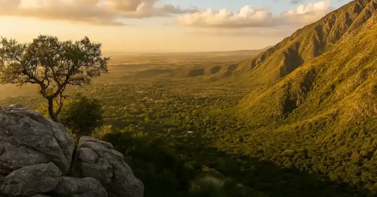 Vista panorámica del valle desde el mirador del Filo de los Comechingones en Merlo, San Luis, con montañas verdes y luz dorada del atardecer.
