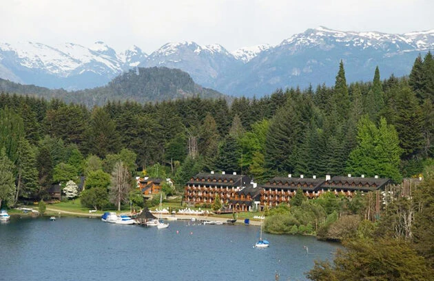 Vista de Bahía Manzano en Villa La Angostura, con hoteles, embarcaciones y montañas nevadas de fondo en la Patagonia argentina