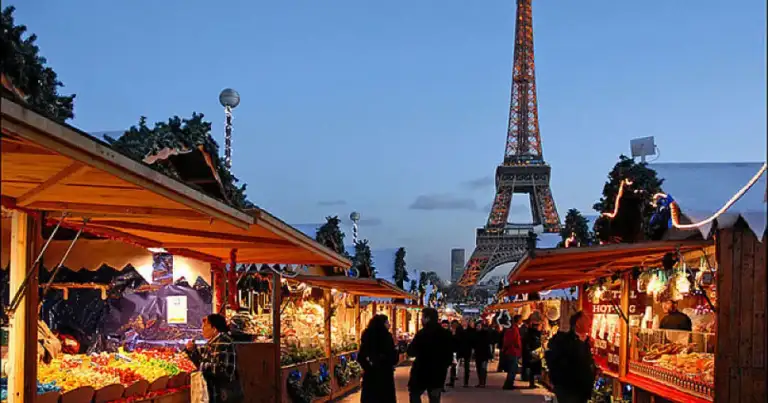 Puesto de mercado navideño con decoración dorada y visitantes por la noche