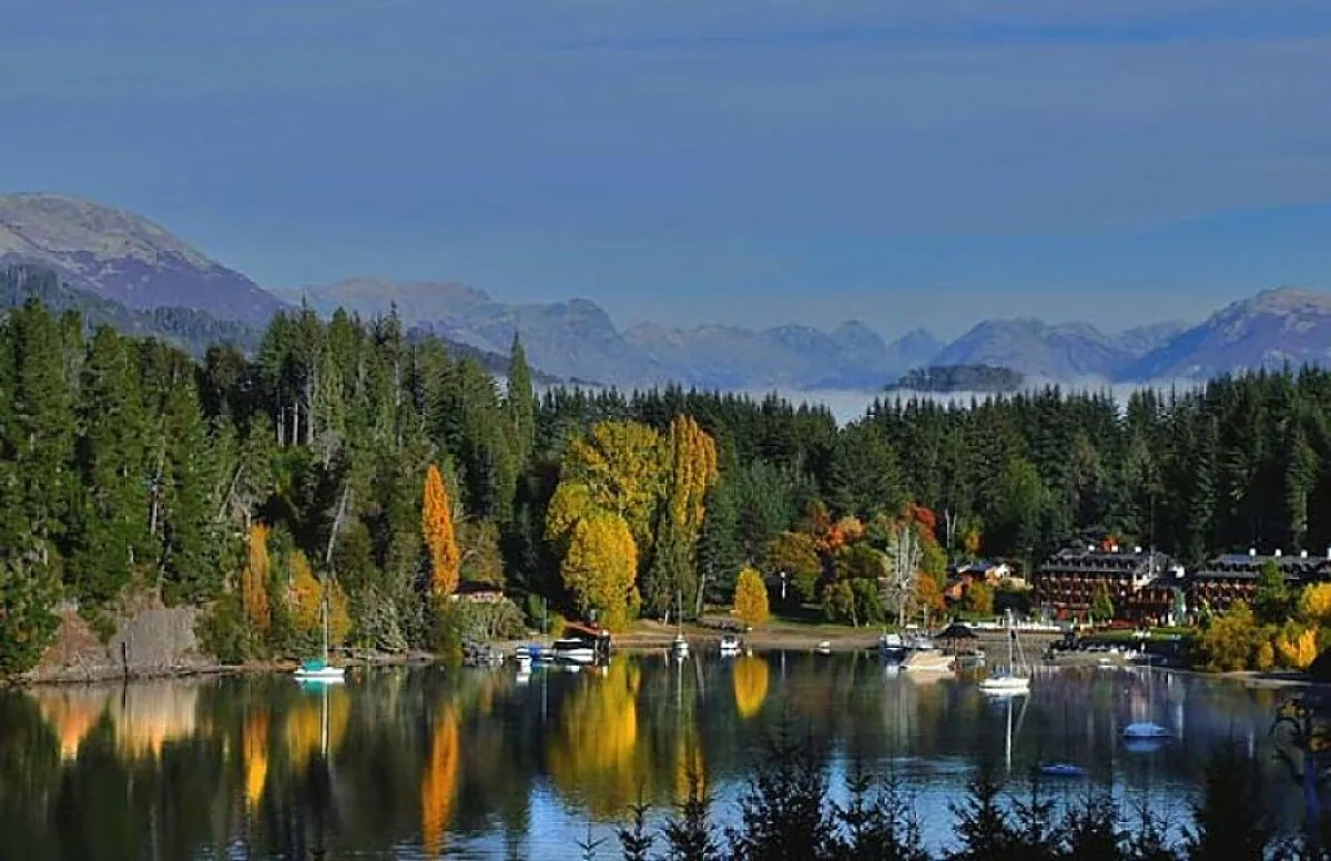 Vista panorámica de Bahía Manzano en Villa La Angostura con bosques, montañas y barcos reflejados en las aguas del Lago Nahuel Huapi