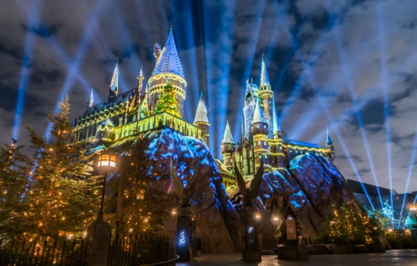 Castillo de fantasía iluminado de noche con luces azules y doradas en parque temático
