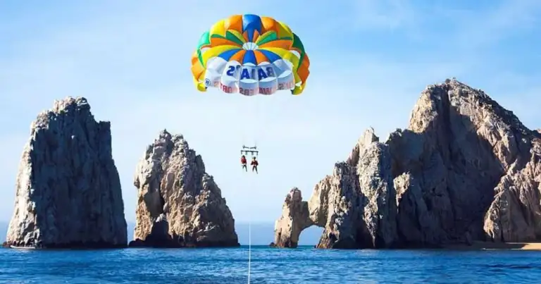 Paracaidista volando sobre océano con formaciones rocosas costeras