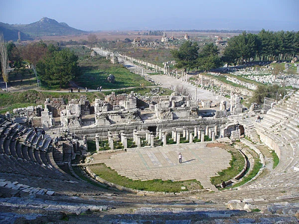 Ruinas de templos y teatro junto a una vía recta en paisaje árido