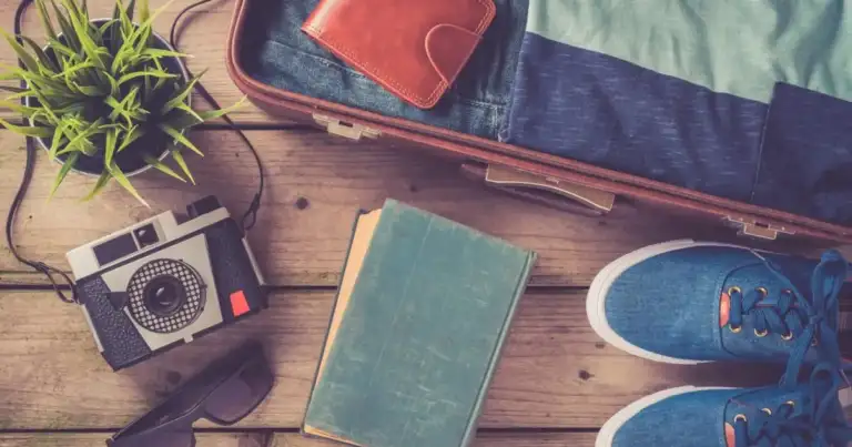 Accesorios de viaje incluyendo cámara, libreta, mapa y calzado dispuestos en una mesa