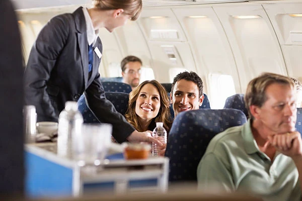 Azafata sonriendo en cabina de avión durante servicio a pasajeros