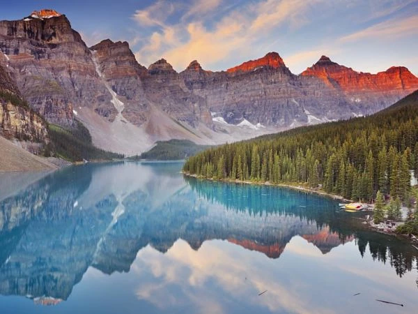 Lago alpino turquesa con reflejos de picos rocosos y bosque de coníferas