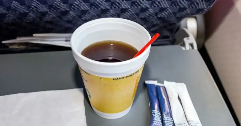 Bebida en taza de plástico en bandeja de asiento de avión