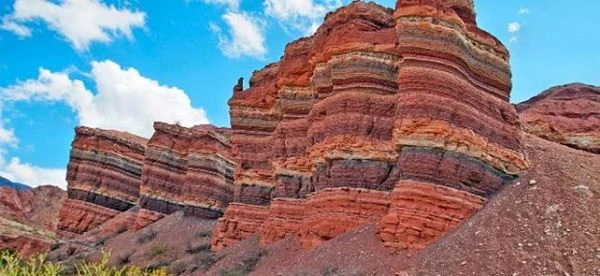 Montaña con capas de roca de colores rojo y marrón en paisaje desértico árido
