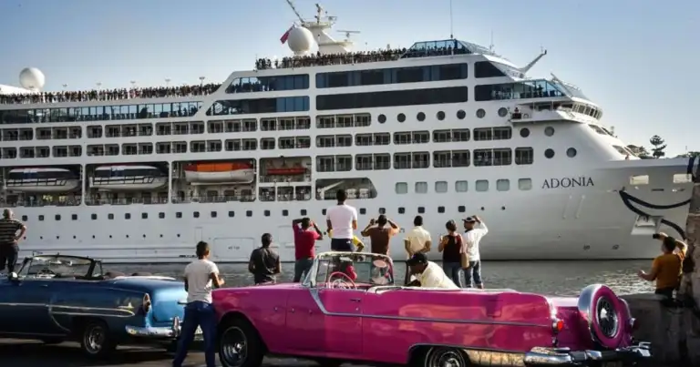 Crucero grande en puerto con automóvil clásico rosa en el muelle