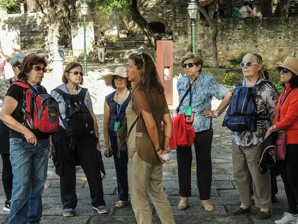 Grupo de turistas escuchando guía en patio histórico con muros de piedra