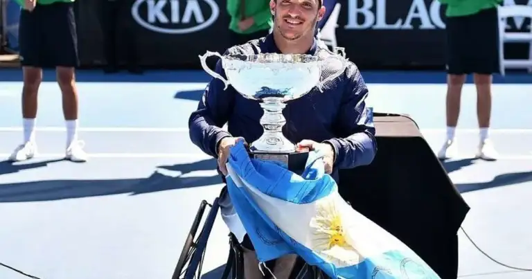 Persona ganadora en cancha de tenis sosteniendo copa y bandera argentina