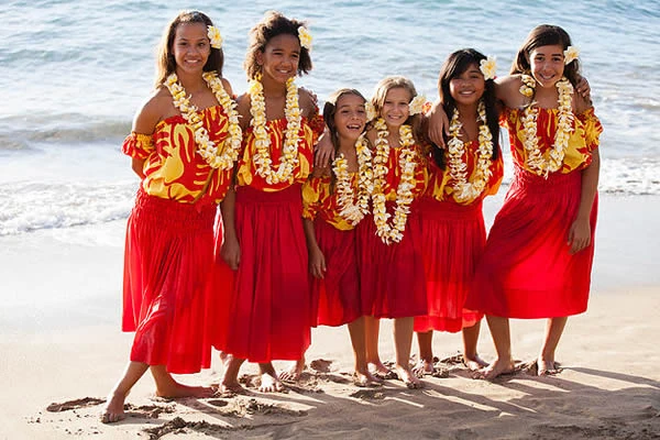 Mujeres en trajes rojos con collar de flores en playa tropical
