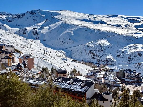 Estación de esquí en montaña nevada con pistas, edificios y teleféricos