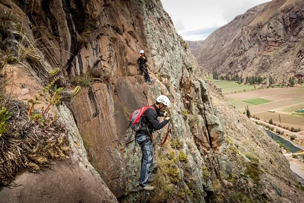 Persona escalando con arnés en la vía ferrata que lleva a las cápsulas del Skylodge