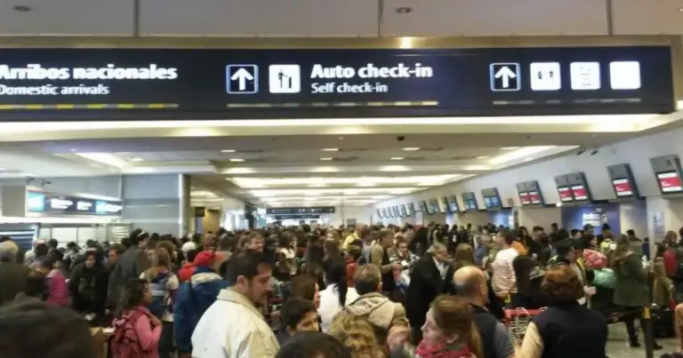 Aglomeración de pasajeros aguardando en zona de check-in del aeropuerto