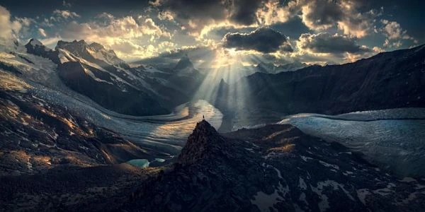 Alpes suizos con rayos de sol a través de las nubes sobre montañas nevadas