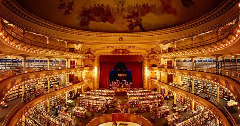 Librería de múltiples pisos con balcones, decoración ornada e iluminación dorada
