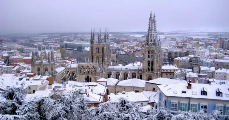 Catedral gótica con dos torres puntiagudas rodeada de nieve en ciudad invernal