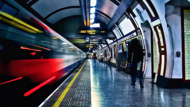 estacion de metro,pasa un tren y un hombre camina por elanden