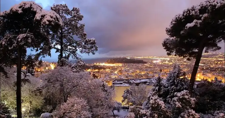 Panorama de ciudad nevada en atardecer con tonos rosados en cielo