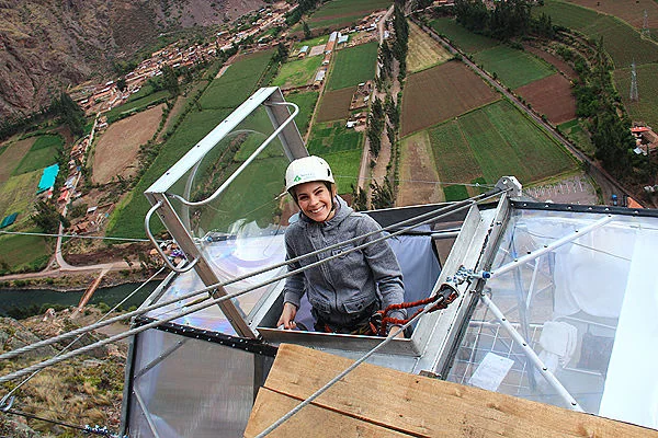 Hombre con arnés saliendo por la escotilla de una cápsula colgante en el Skylodge