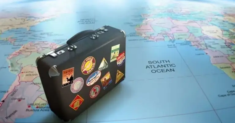 Maleta vintage cubierta de pegatinas de viajes sobre mapa del mundo