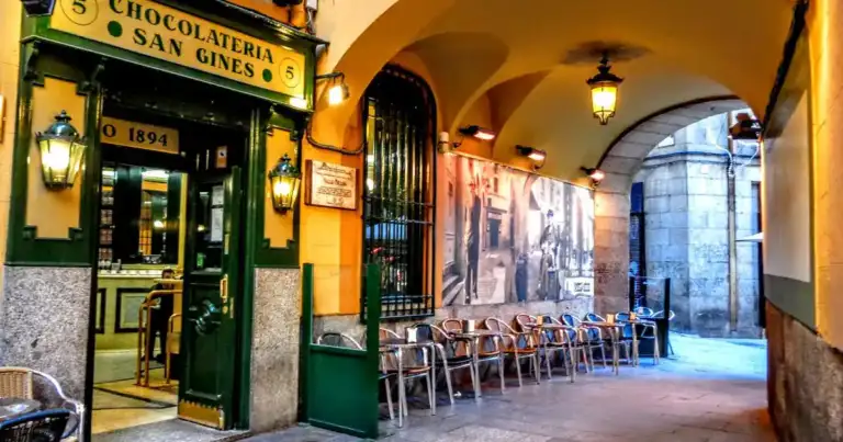 Tienda histórica de chocolate con letrero amarillo bajo arco de piedra