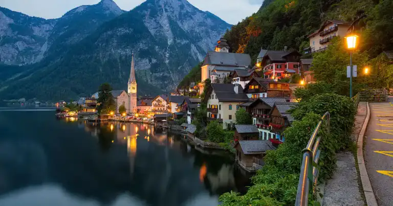 Pueblo histórico junto a lago alpino con iglesia y montañas nevadas