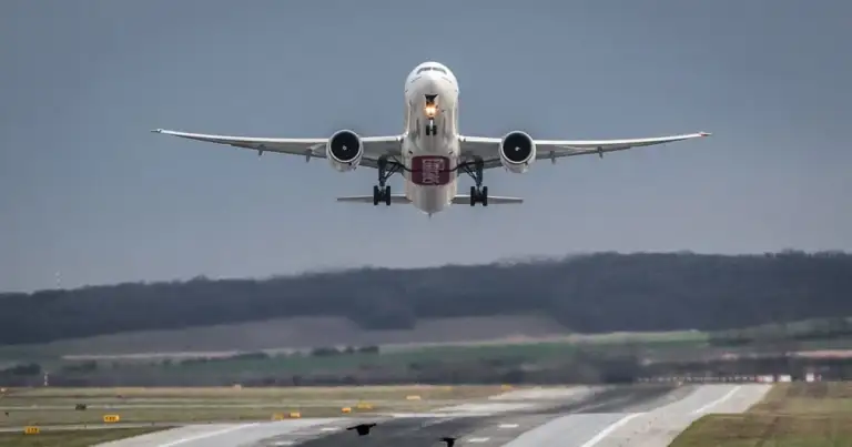 Avión despegando de pista de aterrizaje sobre paisaje verde