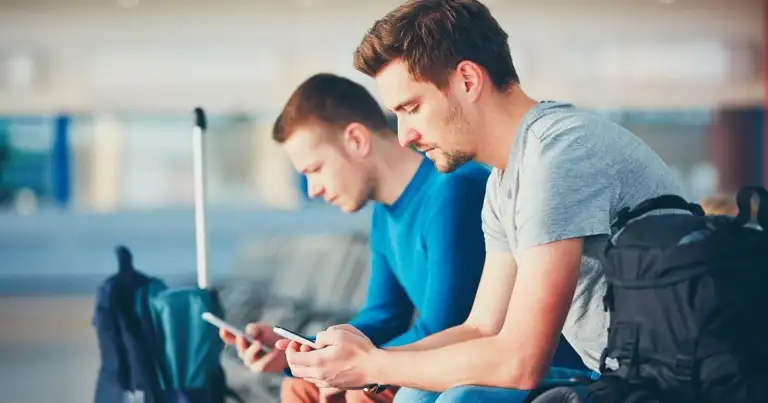 Dos adolescentes observando pantalla de teléfono celular