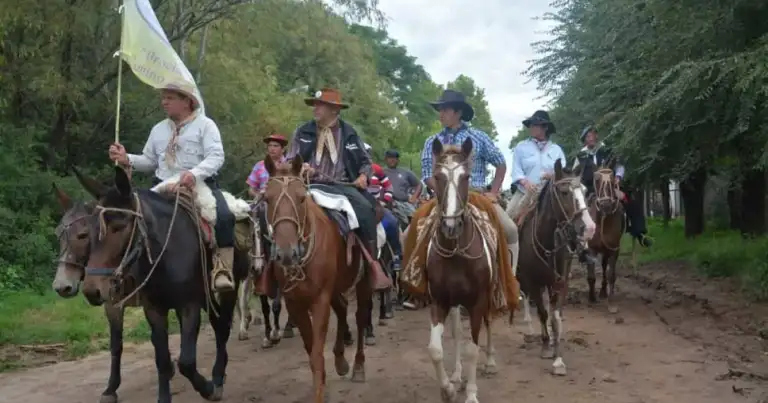 Grupo de jinetes en cabalgata sobre camino de tierra rodeado de vegetación