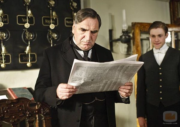 El mayordomo Carson lee el periódico junto a la señora Hughes en la zona de servicio de Downton Abbey