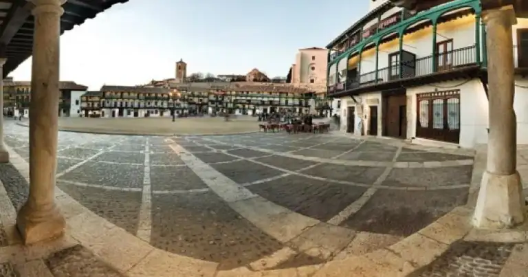 Plaza de pueblo medieval rodeada de casas coloniales de colores
