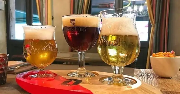 Tres vasos de cerveza belga de diferentes tonalidades sobre tabla de madera