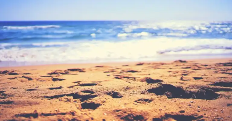 Playa con arena y olas de mar al atardecer